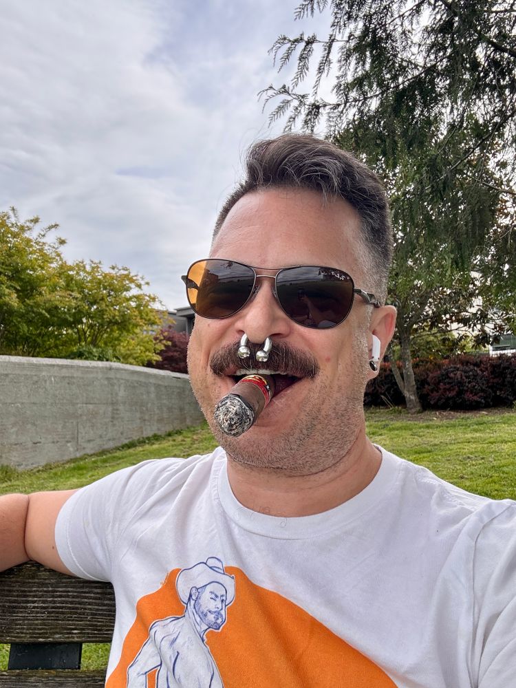 Man in sunglasses smokes cigar at lakeside park
