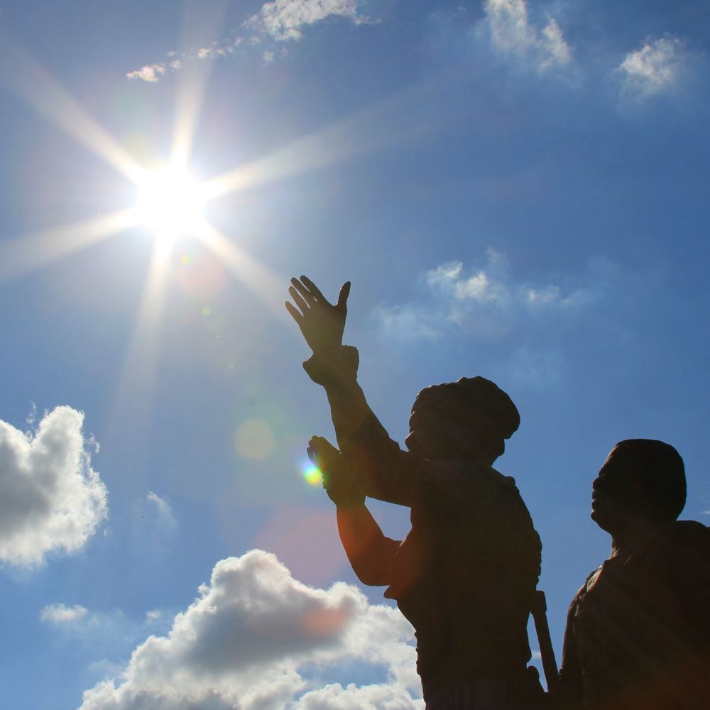 Picture of Juneteenth monument at the G. W. Carver Center, Austin, Texas, showing a man looking upwards and a woman raising her hands toward the sky, where a bright sun is shining. Photo by Jennifer Rangubphai; used under CC4.0 license.