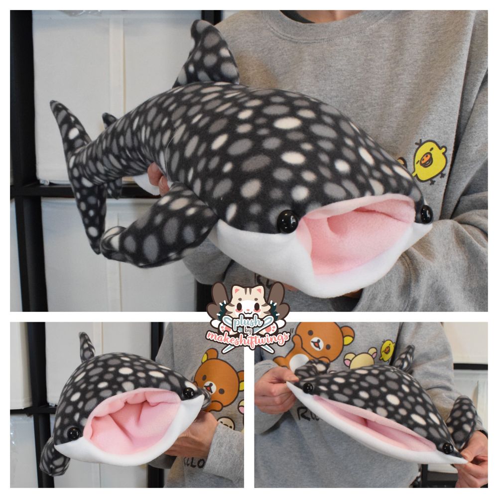 A plush of a black and white whale shark with an open pink mouth