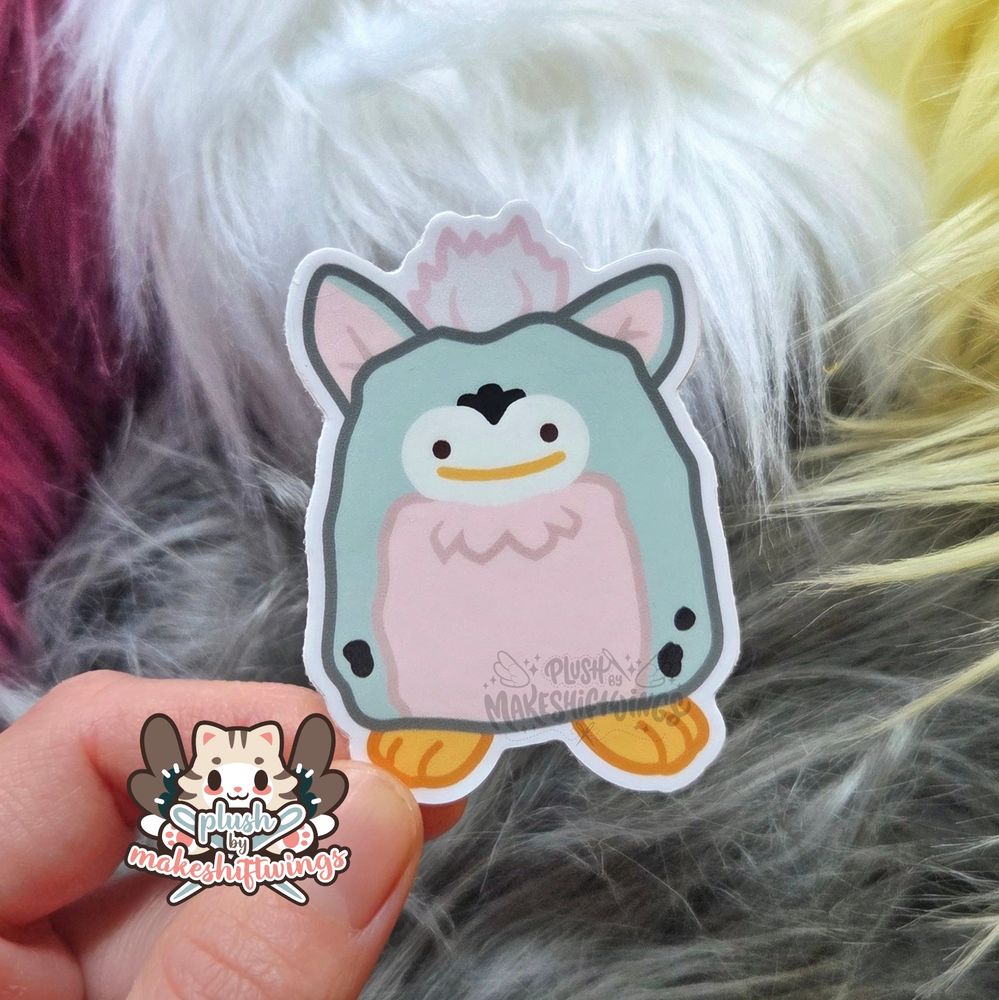 A sticker of a grey, pink, and white furby with a ditto face