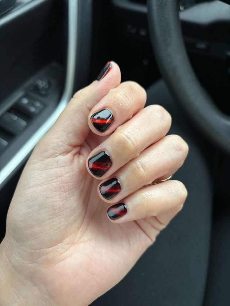 A close up of my left hand showing my nails painted red. There’s a more red stripe through the middle of each nail, and darker to either side. 