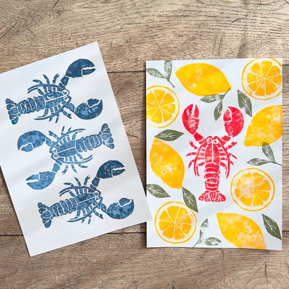 A Lino print of 3 blue lobsters, next to another one of one red one surrounded my lemons. 