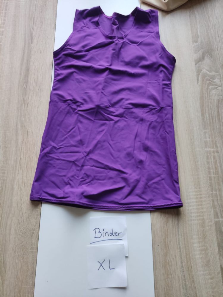 Ein hüftlanger, lilafarbener Binder. Davor liegen kleine Zettel auf denen "Binder Größe XL" steht.