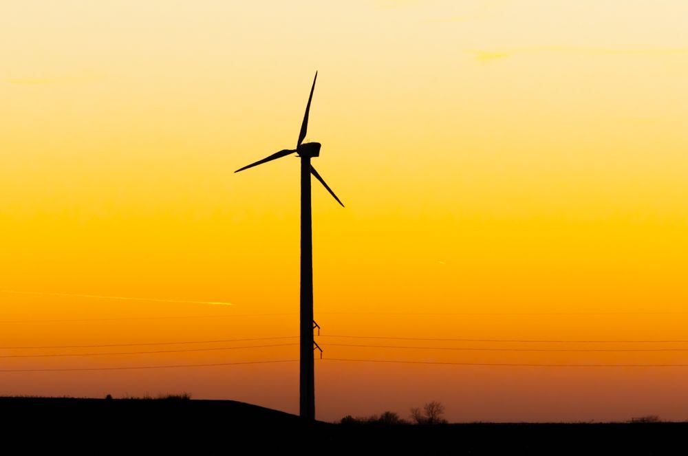 A lone windmill gazes upon a setting sun, reminiscing on the days of it's youth.