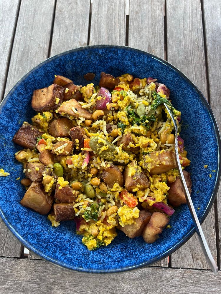 Blue bowl of a vegan meal. Black eye pea soup over basmati rice and baked potato cubes. 
