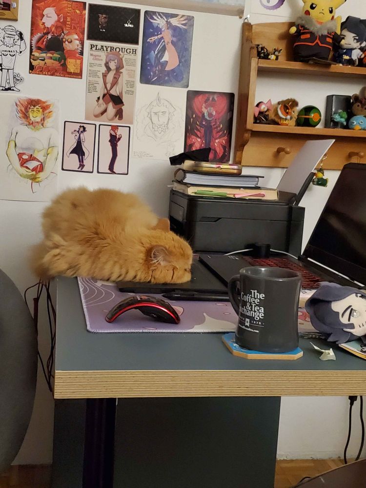 zelos laying on sam's desk in front of his lysandre wall. zelos has curled up so that his head is entirely on top of sam's tablet. he looks like a big worm.