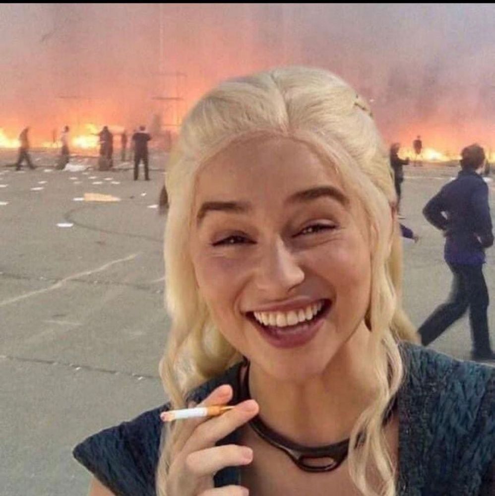 Queen Daenerys Targaryen from The Game of Thrones TV series. Smoking a cigarette smiling with chaos brewing in the background