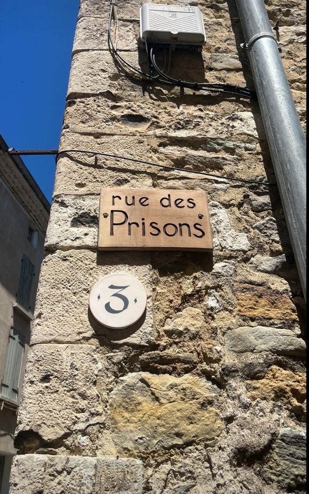 Photo d'un panneau qui indique le nom d'une rue, la Rue des Prisons, à Dieulefit. 