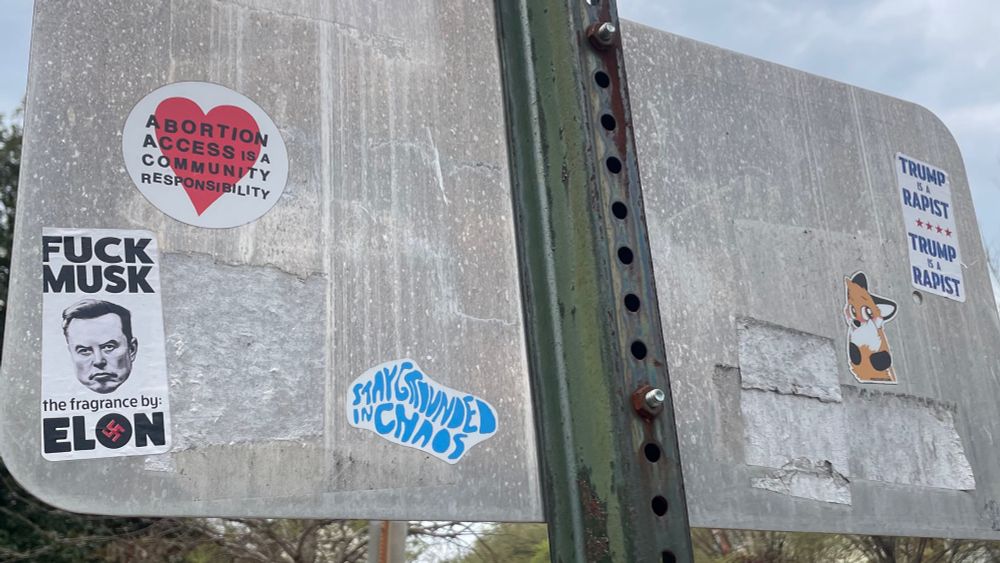 The back of a street sign with pro abortion, anti musk and anti trump stickers: ABORTION ACCESS IS A COMMUNITY RESPONSIBILITY

FUCK MUSK
the fragrance by:
ELON

TRUMP IS A RAPIST