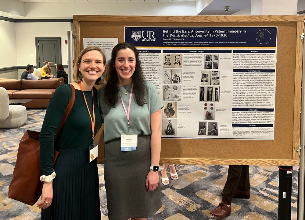 Me (a white woman with blonde hair in a green skirt and top) and my student Bella (a white woman with dark hair and a grey pencil skirt) in front of her poster titled "Behind the Bars: Anonymity in Patient Imagery in the British Medical Journal, 1870-1930".