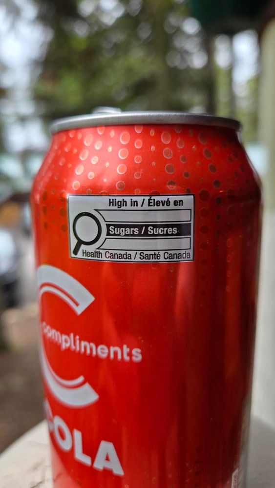 Red can of cola with a "high in sugar" front-of-package label.