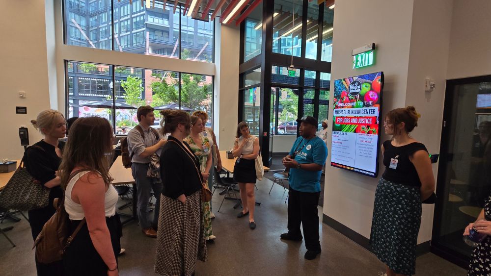 CSPI interns and staff stand in the lobby of DC Central Kitchen as a staff member gives a tour of the building.