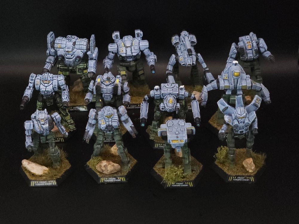 12 miniatures painted in Crater Cobras colors. Light blue on top with green camoflage on bottom. Displayed with a black backdrop.