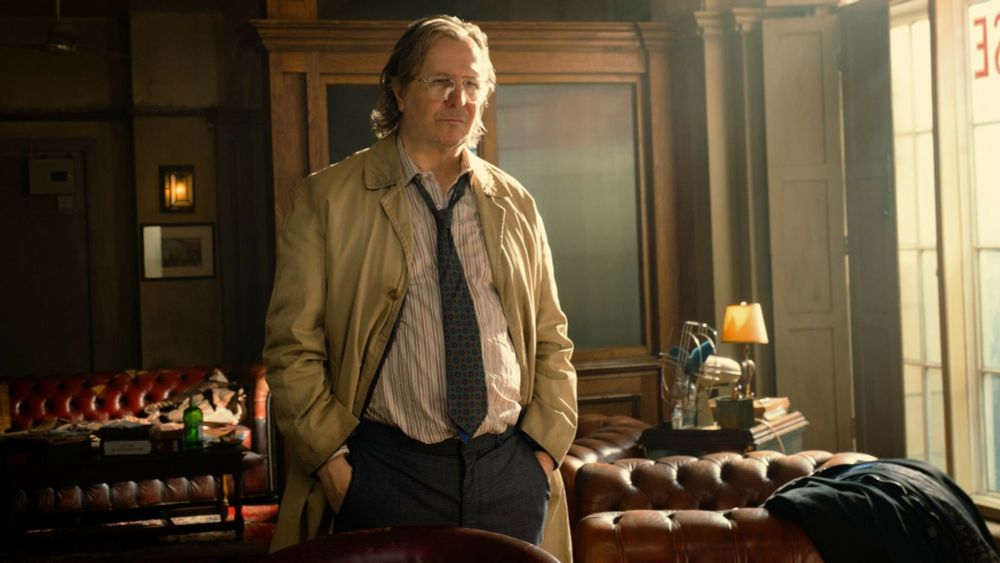 Gary Oldman from Slow Horses looking sloppy, fat, and unkempt - his tie loose, his hair messy and the air looking vaguely Smokey in some kind of parlor.