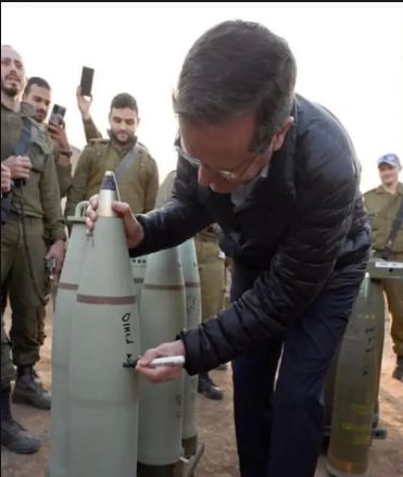 Israeli president Herzog is photographed surrounded by IDF forces, signing bombs before they are used in Israel's genocide. 