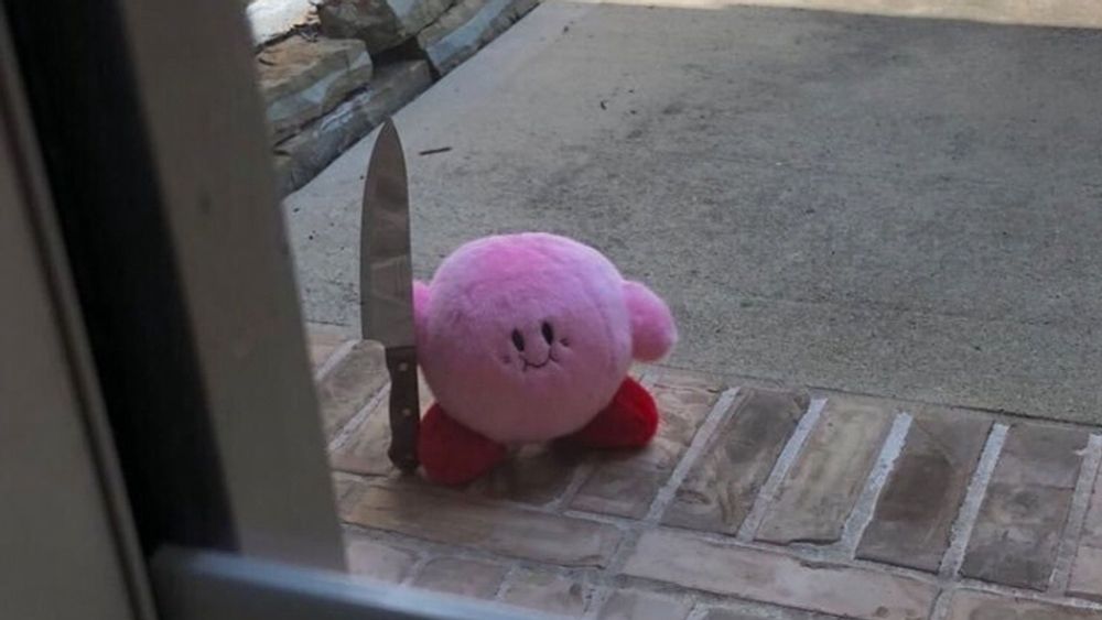 Plush of Kirby holding a giant butcher’s knife, standing just outside the window.