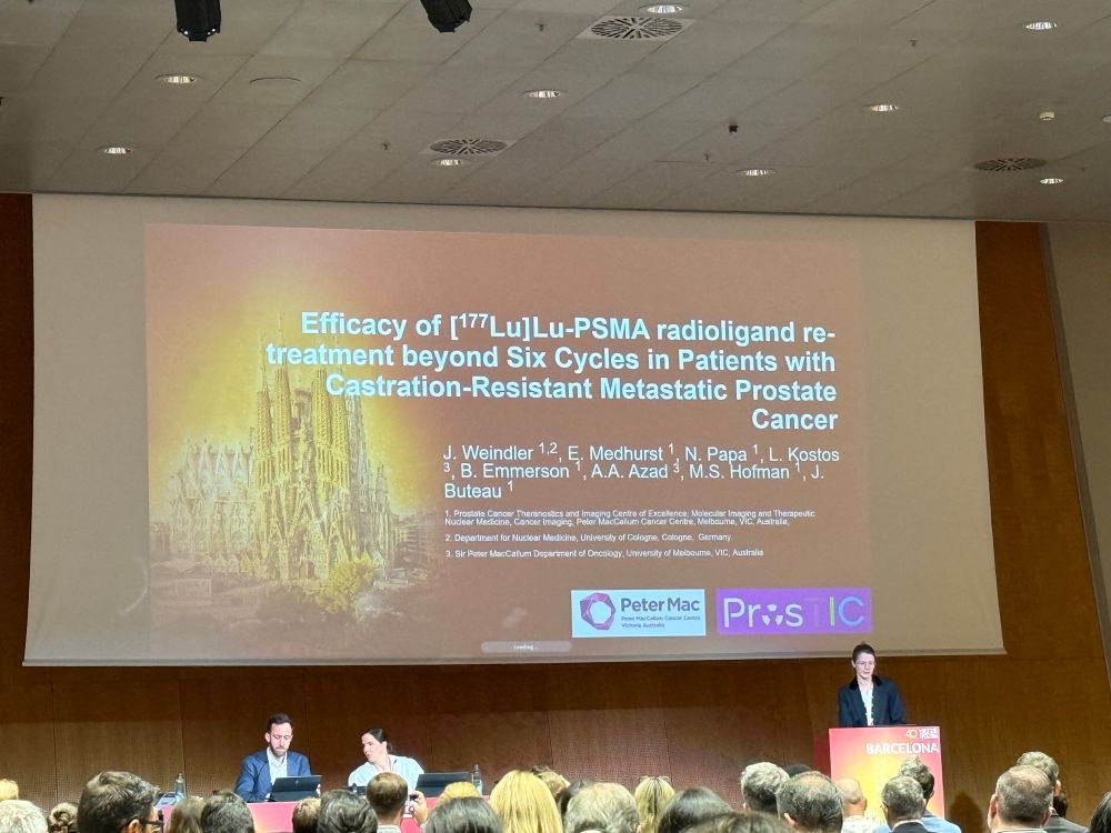 Academic presentation by Dr Jasmin Weindler, with the presenter standing at the lecture in front of her title slide ‘Efficacy of LuPSMA beyond 6 cycles in patients with mCRPC’.