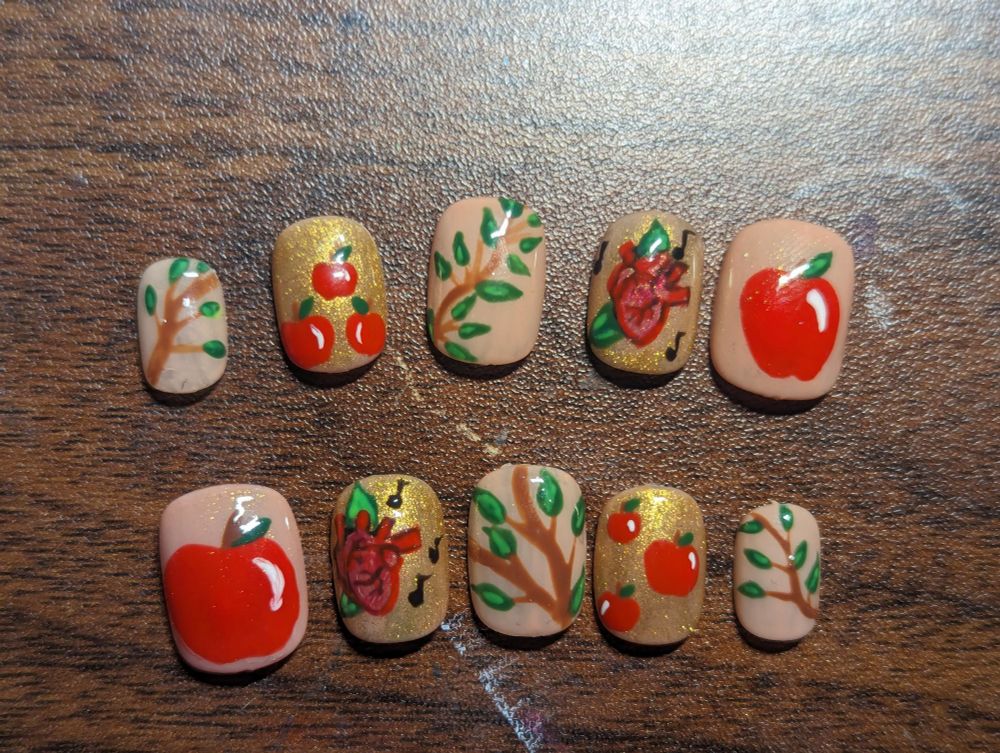 Natural length nails beige and gold with red apples leafy branches and a human heart with music notes