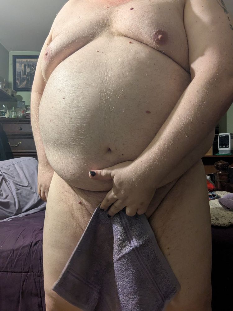 A chubby white person with a small towel covering their small cock