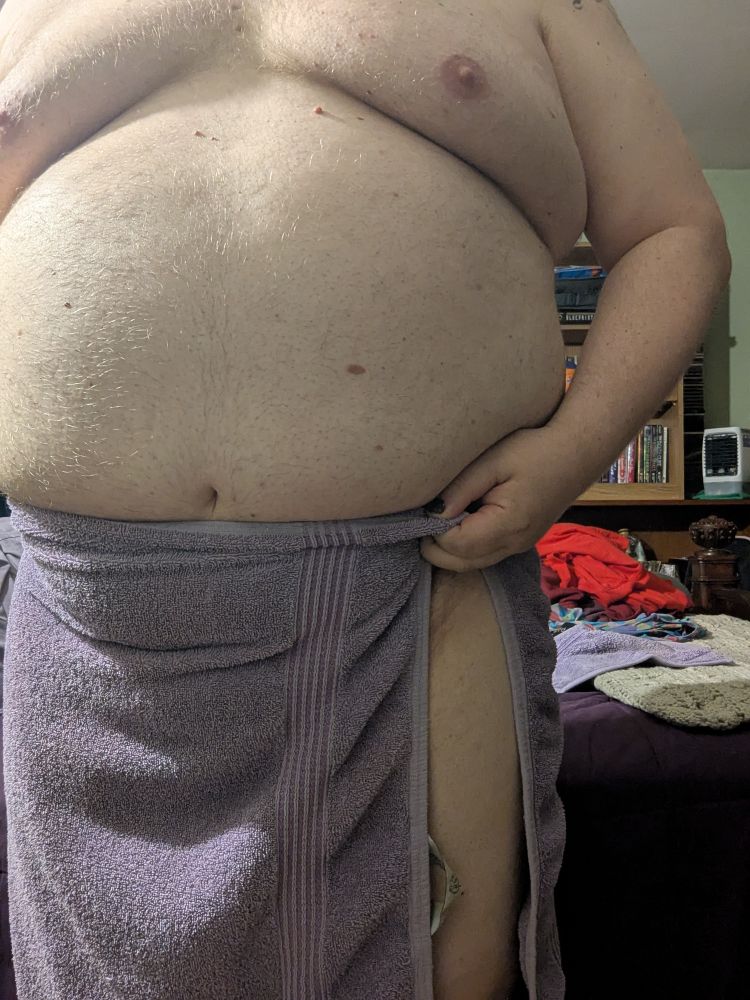 A chubby white person wearing only a towel with one leg peeking out