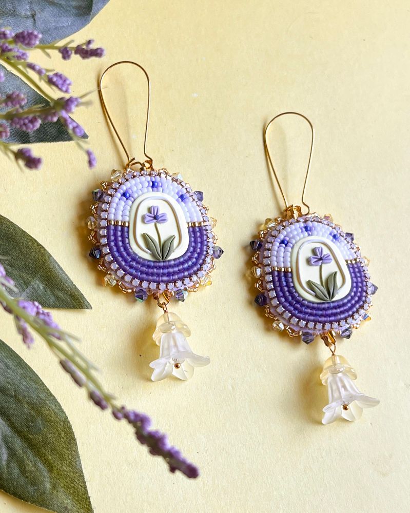 white and purple beaded earrings with polymer clay centers with purple flowers 