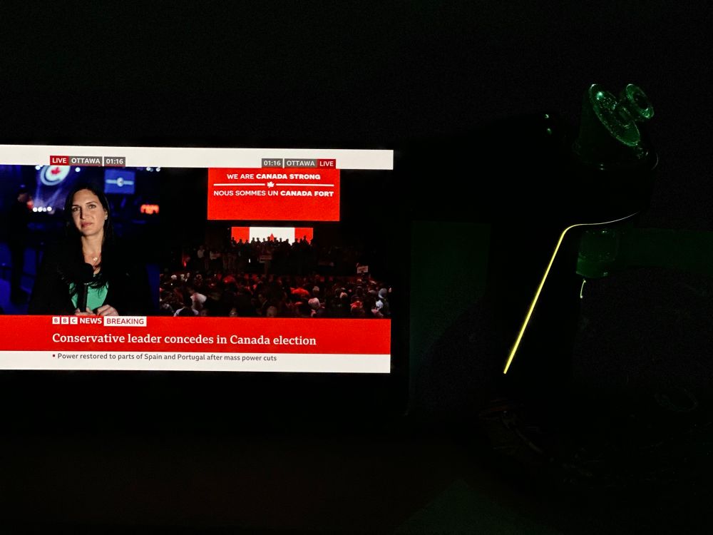 A picture of tablet showing the BBC announcing the Conservative Party of Canada has conceded the election next to an enormous electric dab rig. 