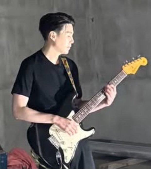 Yoongi nonchalantly picking guitar. He’s got black hair with undercut, black tee, black pants and I love him ok 