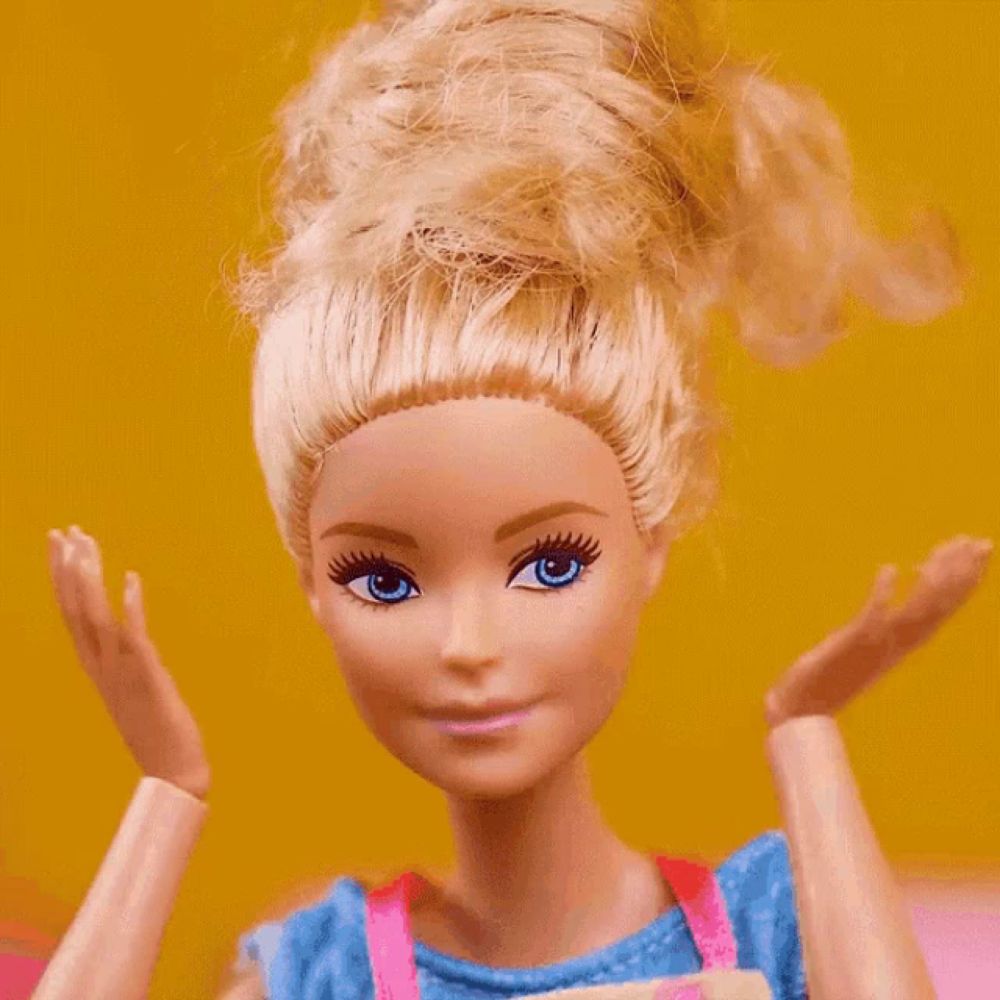 a barbie doll with blonde hair and blue eyes holds her hands to her face