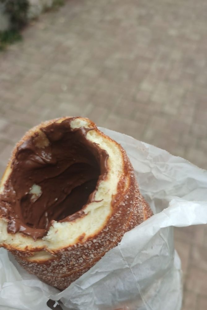 Foto de um Trdelník recheado de chocolate, mas não é aqueles tredelník fininho pequeno mixuruco que vendem nos lugares turísticos pelo preço de um rim. Esse aqui é gigante, grosso, pesado e massudo com tanto recheio que fica caindo fora, vendido nos subúrbios da cidade a vinte reais (além do preço que você vai pagar com os prejuízos ao seu sistema cardiorespiratorio).