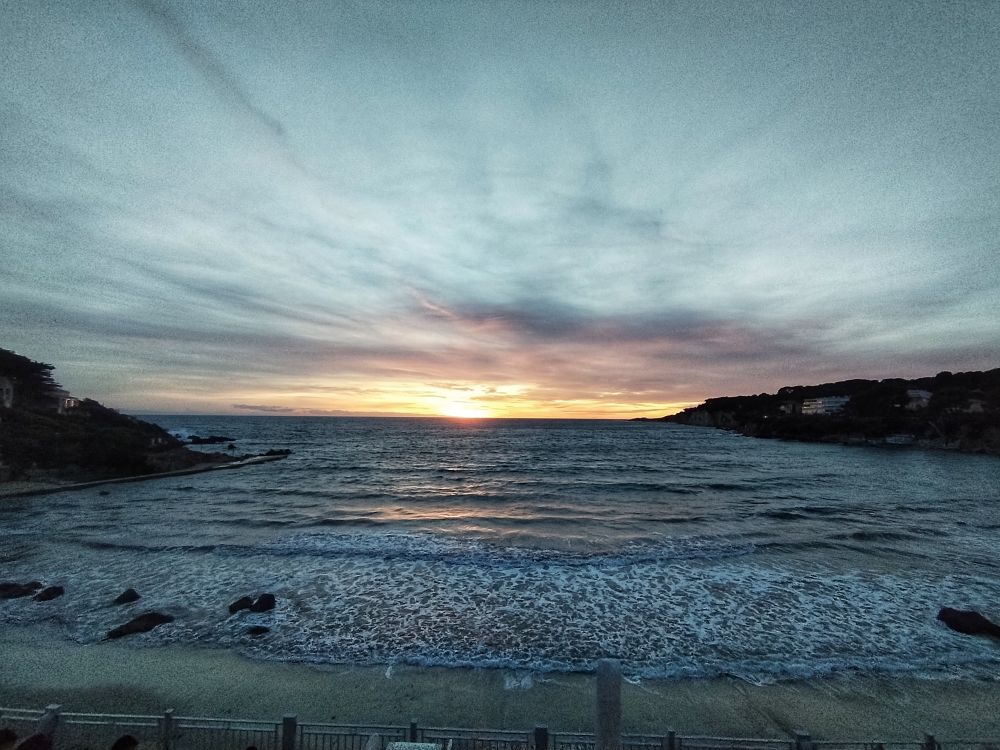 Baie de Portissol en forme de U sur la méditerranée tourné plein ouest sous in ciel nuageux au soleil couchant 