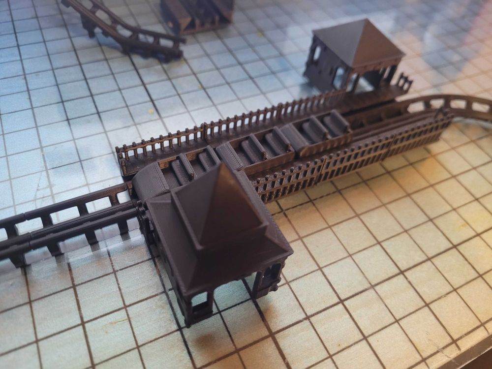 a photo of the basic track shown in the previous 2 images, 3d printed in black pla. for scale, a station piece is 34mm x 34mm