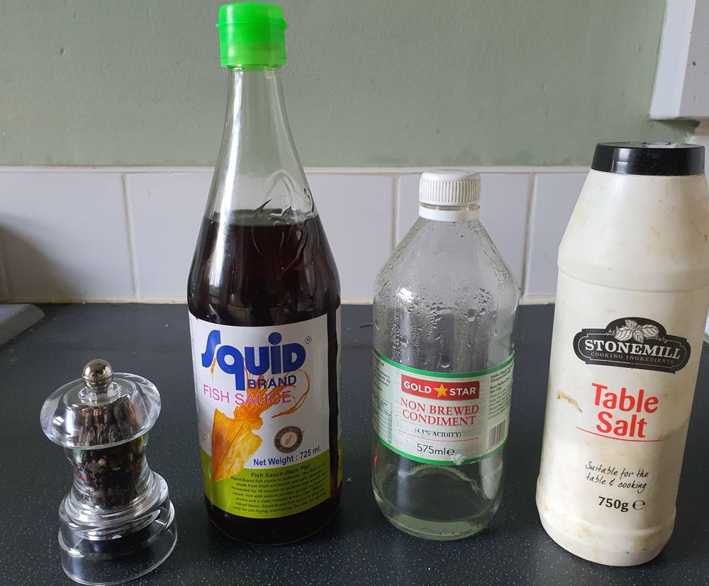 Kitchen worktop with perspex pepper grinder; bottle of fish sauce; bottle of non-brewed condiment and flask of table salt.
I propose moving fish sauce from animal product to condiment. Its the only way I'd consider going vegan. Let's face it anchovies are barely animal anyway, I've had stronger emotional ties to some trees and shrubbery. These vegan fascists have no moral argument to oppose this move, and I personally think fish sauce or cheese is the only way to make a pure veg diet palatable. Send us your thoughts.