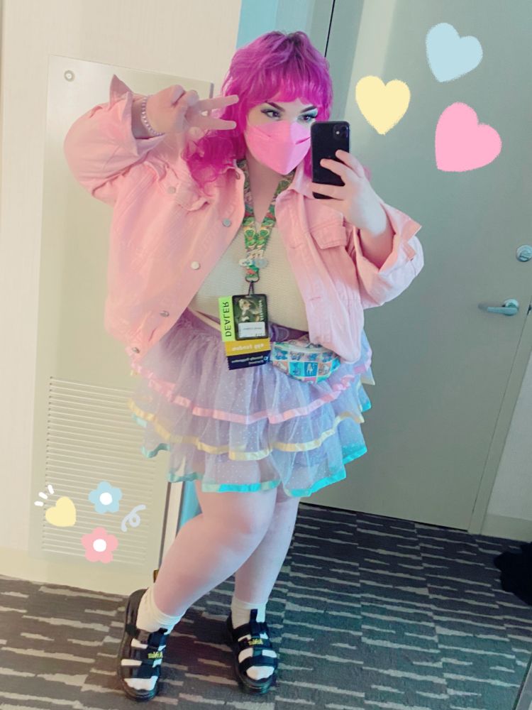 person in pastel clothing posing with a peace sign 