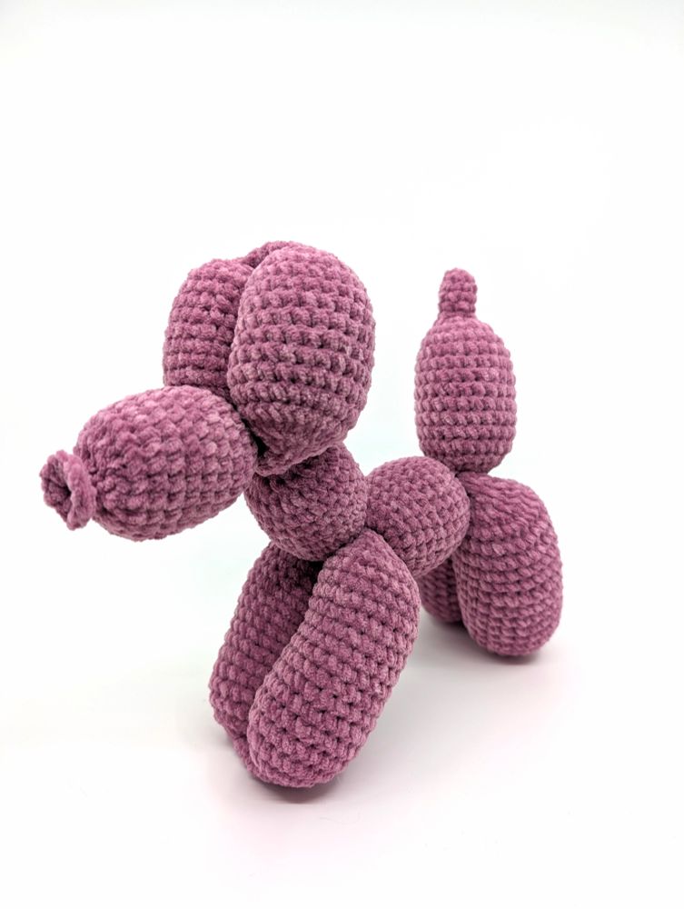 A balloon dog crocheted out of soft pink yarn
