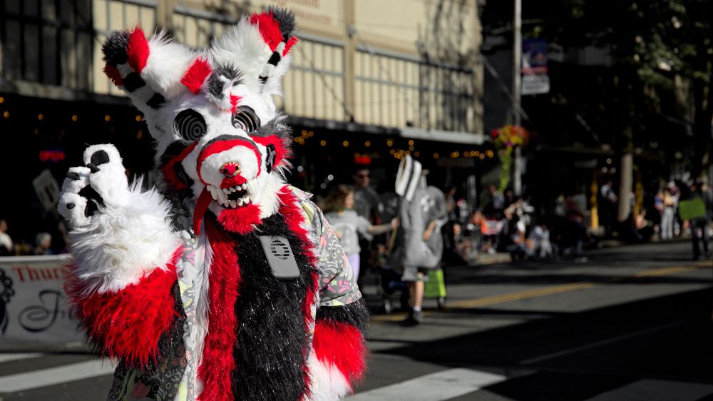 Rainy Day Furries costume character wearing a red black and white animal theme costume with scary eyes, jagged teeth