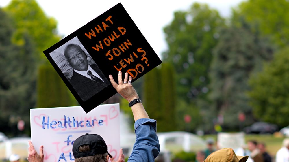 Olympia Washington, person holding sign, what would John Lewis do? with photo of John Lewis, civil rights activist