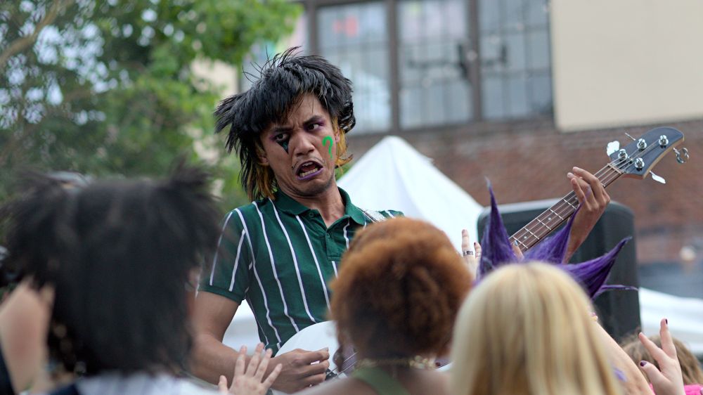 Photo of person playing guitar, facial expressions, face paintings, people watching concert
