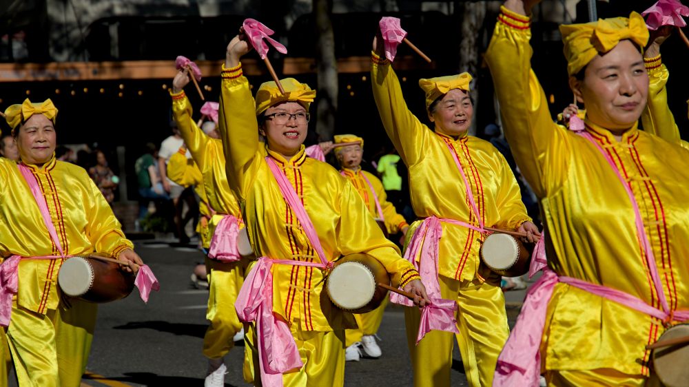Photo of Falun Dafa members wearing yellow and pink clothing carrying traditional waist drums