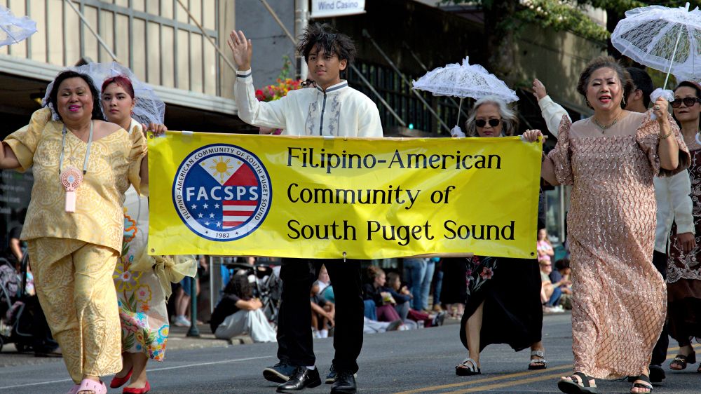 Photo of people in the parade holding a yellow Filipino American Community of South Puget Sound FACSPS 1982 banner.