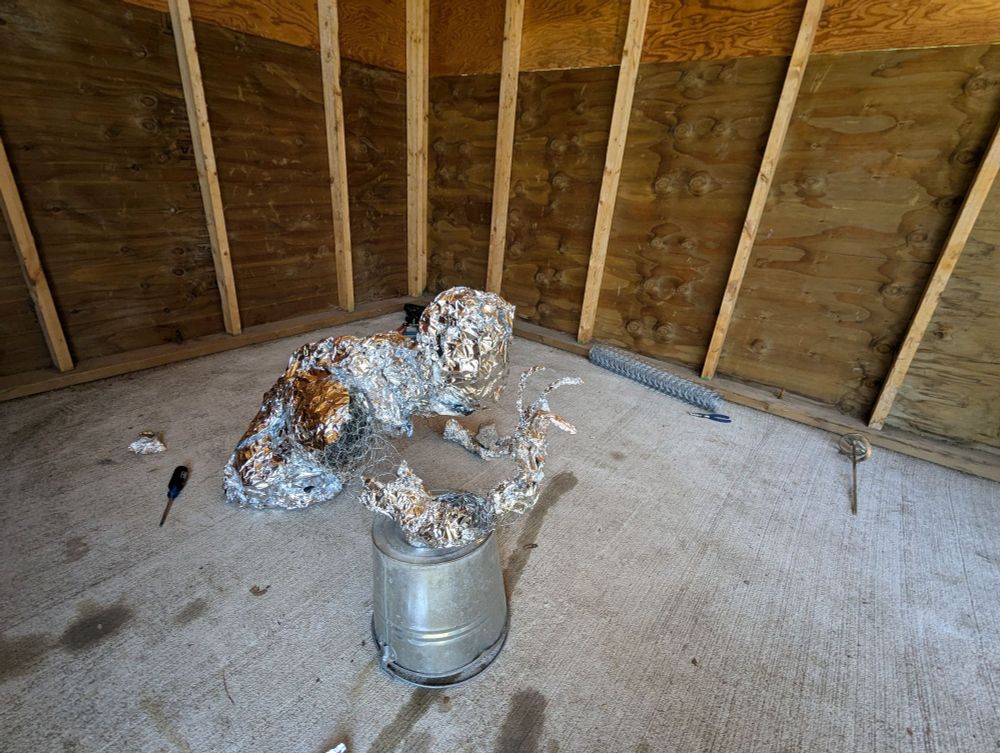 A figure made to look as if coming out of the ground made of tinfoil and chicken wire. (Right side view)