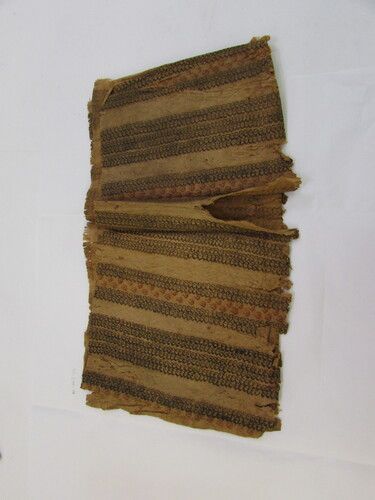 Strip of tapa with design of small printed figures in bands, the center of each band has alternate figures in red. Object was decorated using stamping.