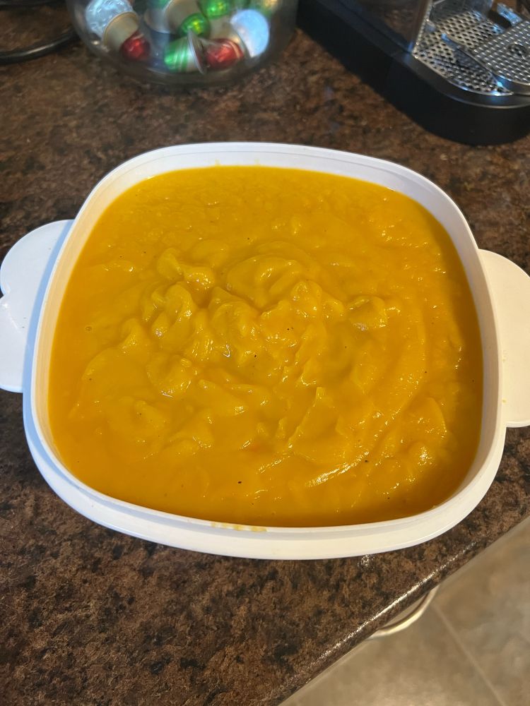 White bowl on a counter filled with butternut squash soup.