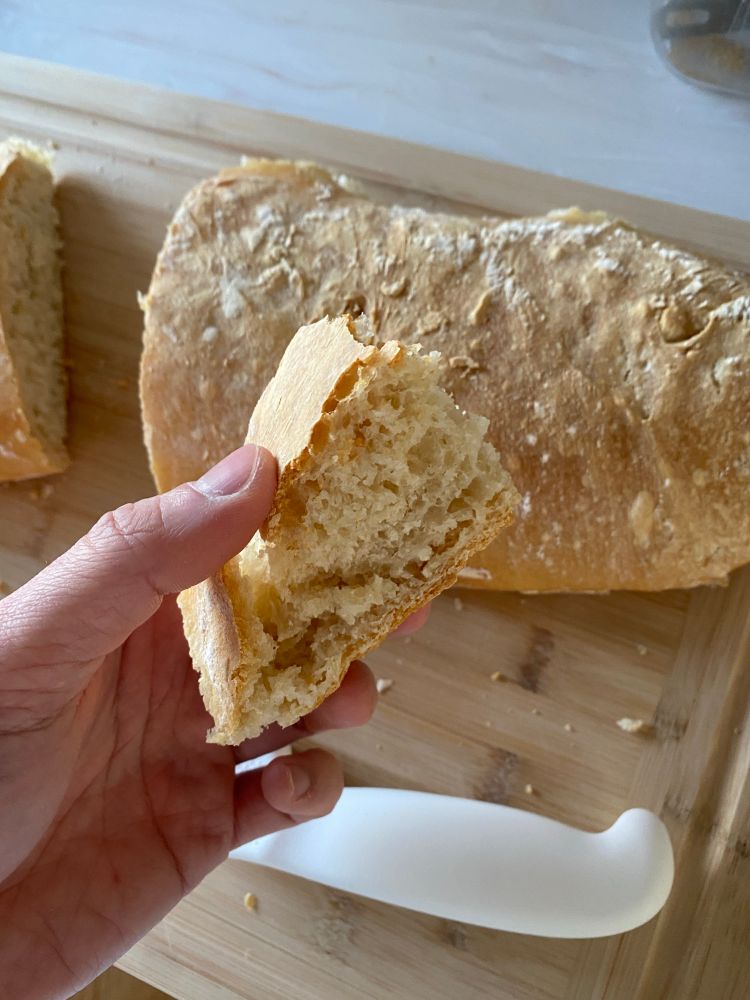 Hand holding a slice of bread from previously mentioned baguettes 