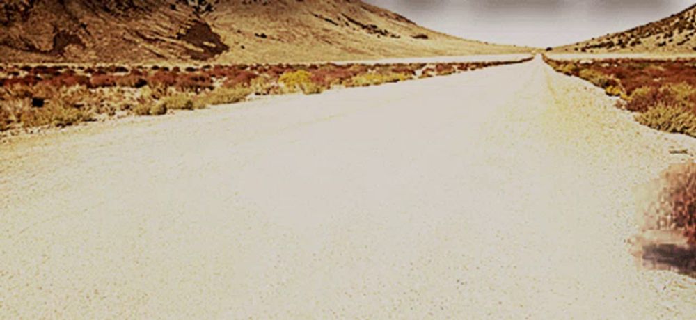 a desert road with mountains in the background