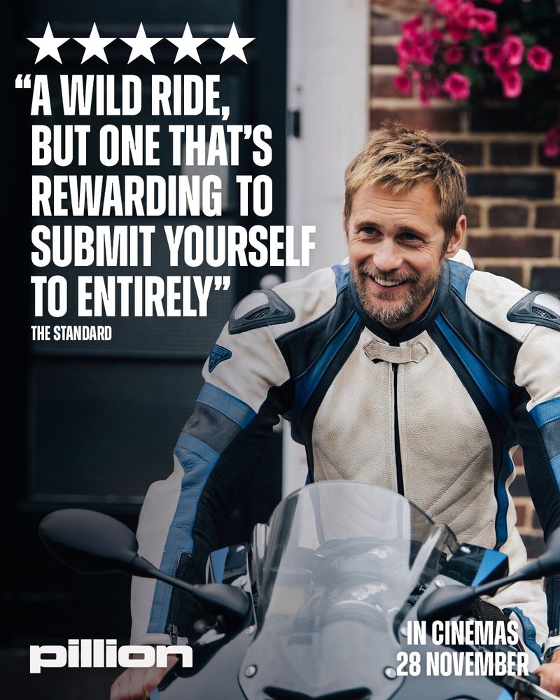 A motorcyclist in a protective leather suit poses on a bike, promoting the film "Pillion," releasing in cinemas on November 28.
