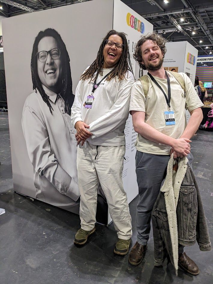 A photo of Jonas and a man posting with a large display. The display has Jonas' face on it. 