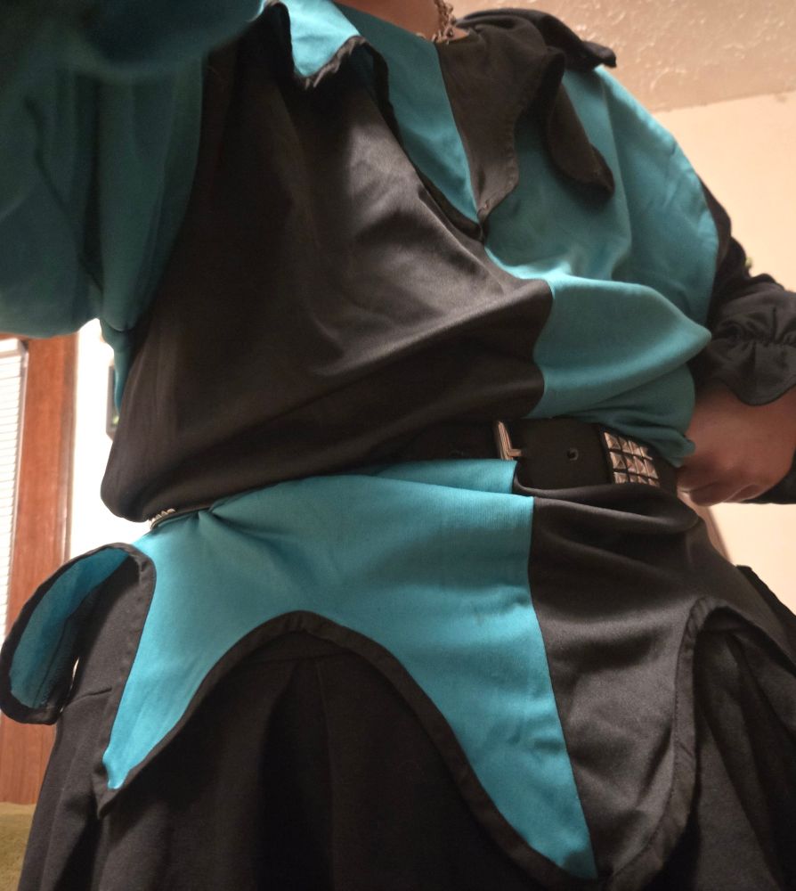 Selfie of just my teal and black jester fit, split jester top with weird little ruff and studded belt 