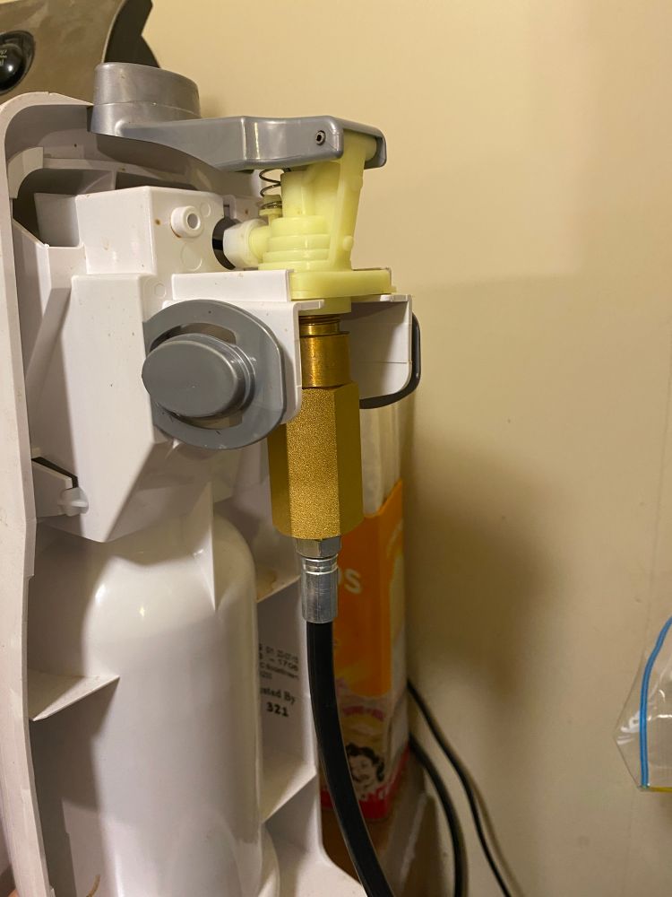 A side view of a sodastream machine with the back off showing a gas hose attached where the bottle should be