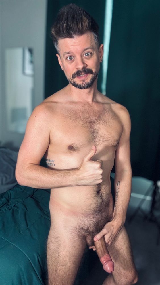 A picture of me, smiling, holding a thumb thumbs up with one hand and my hard fat cock with the other hand