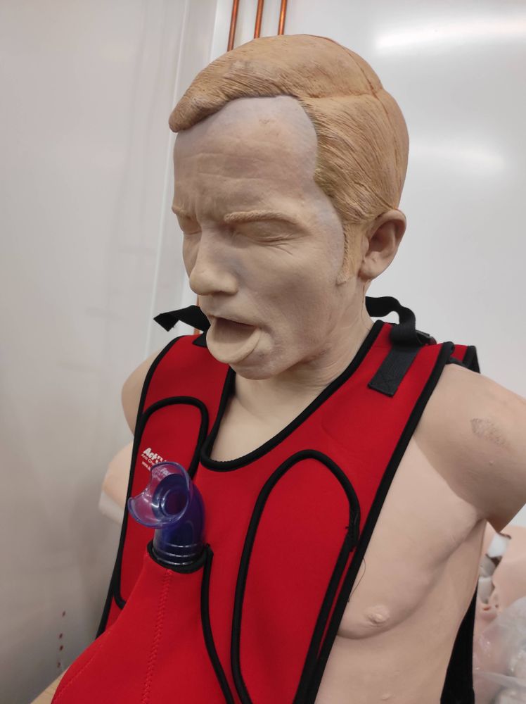 A first aid training dummy with an expression of pain
